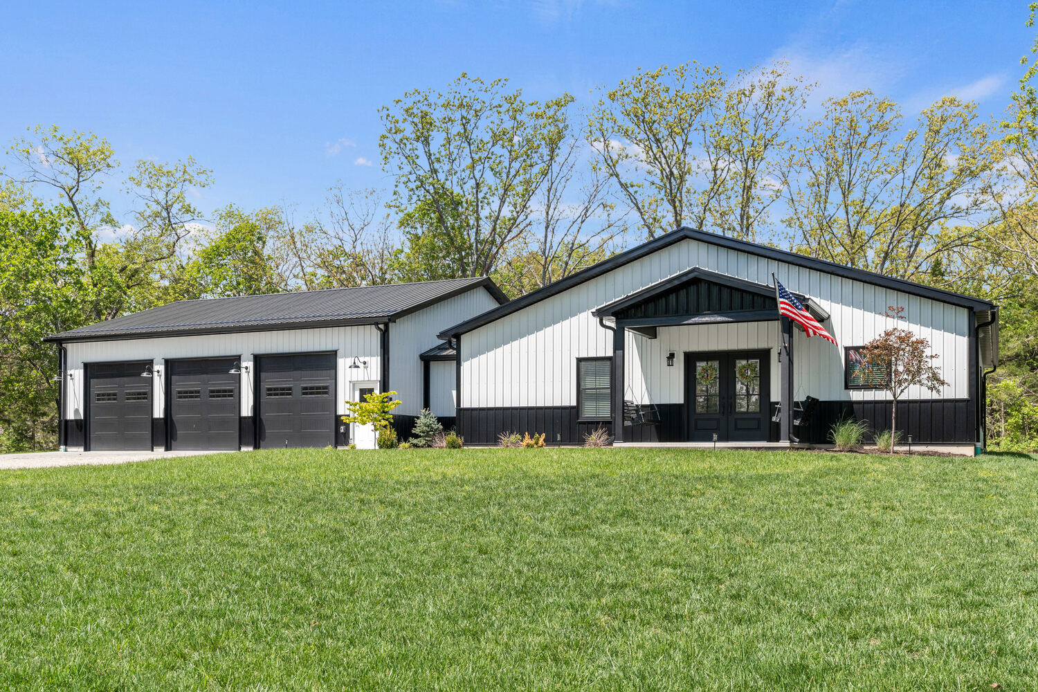 Black and white barndominium on open acreage with an American flag