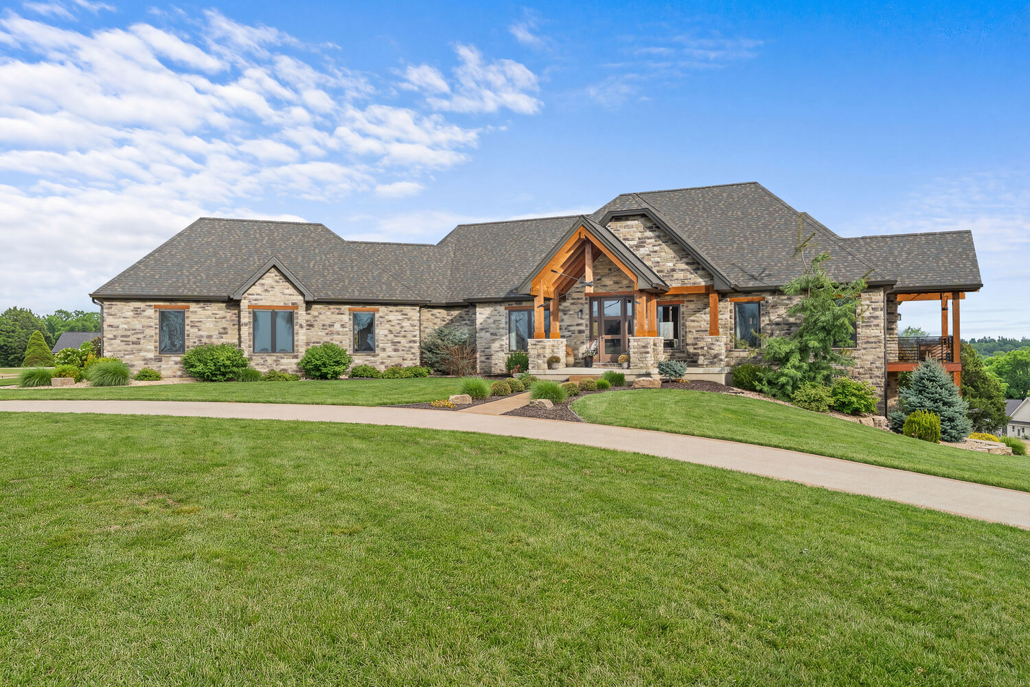 Stone and timber ranch estate with a circular drive under a big Missouri sky