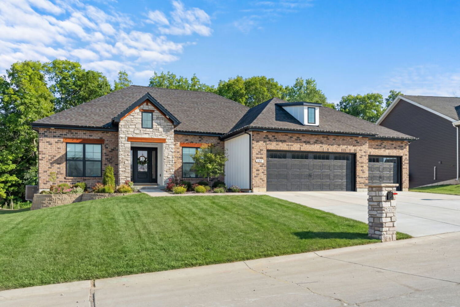 Brick and stone ranch home with a three-car garage and manicured lawn