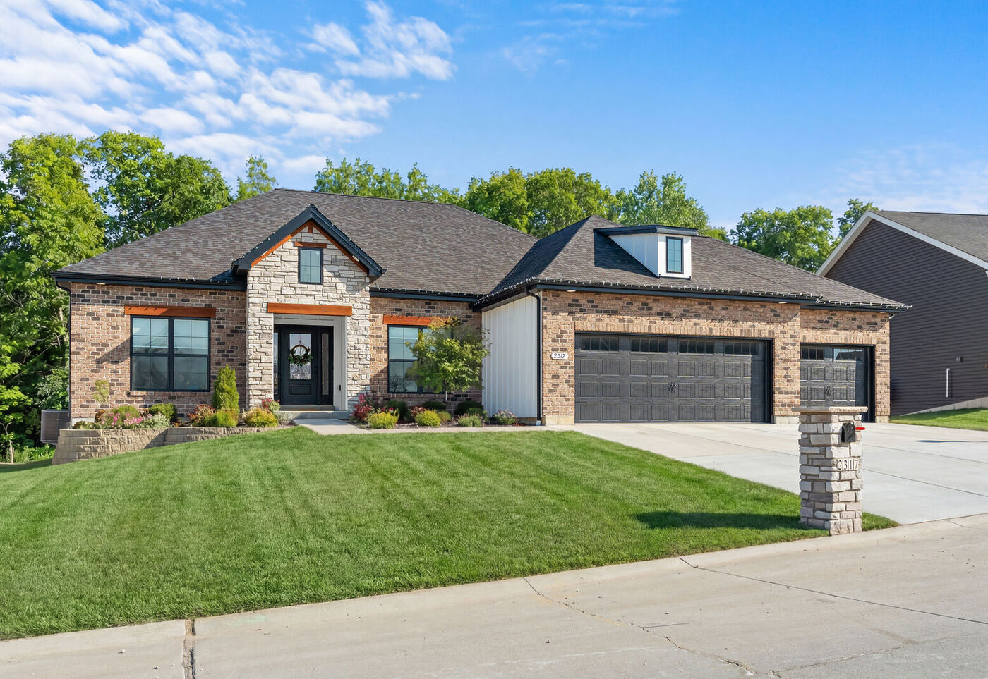 Brick and stone ranch home with a three-car garage and stamped mailbox pillar