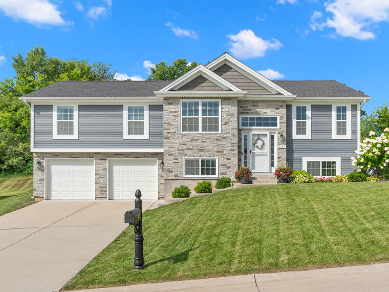 Split-level home with stone accents and manicured lawn