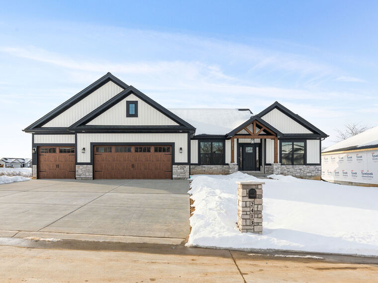 New-construction home with wood garage doors in fresh snow